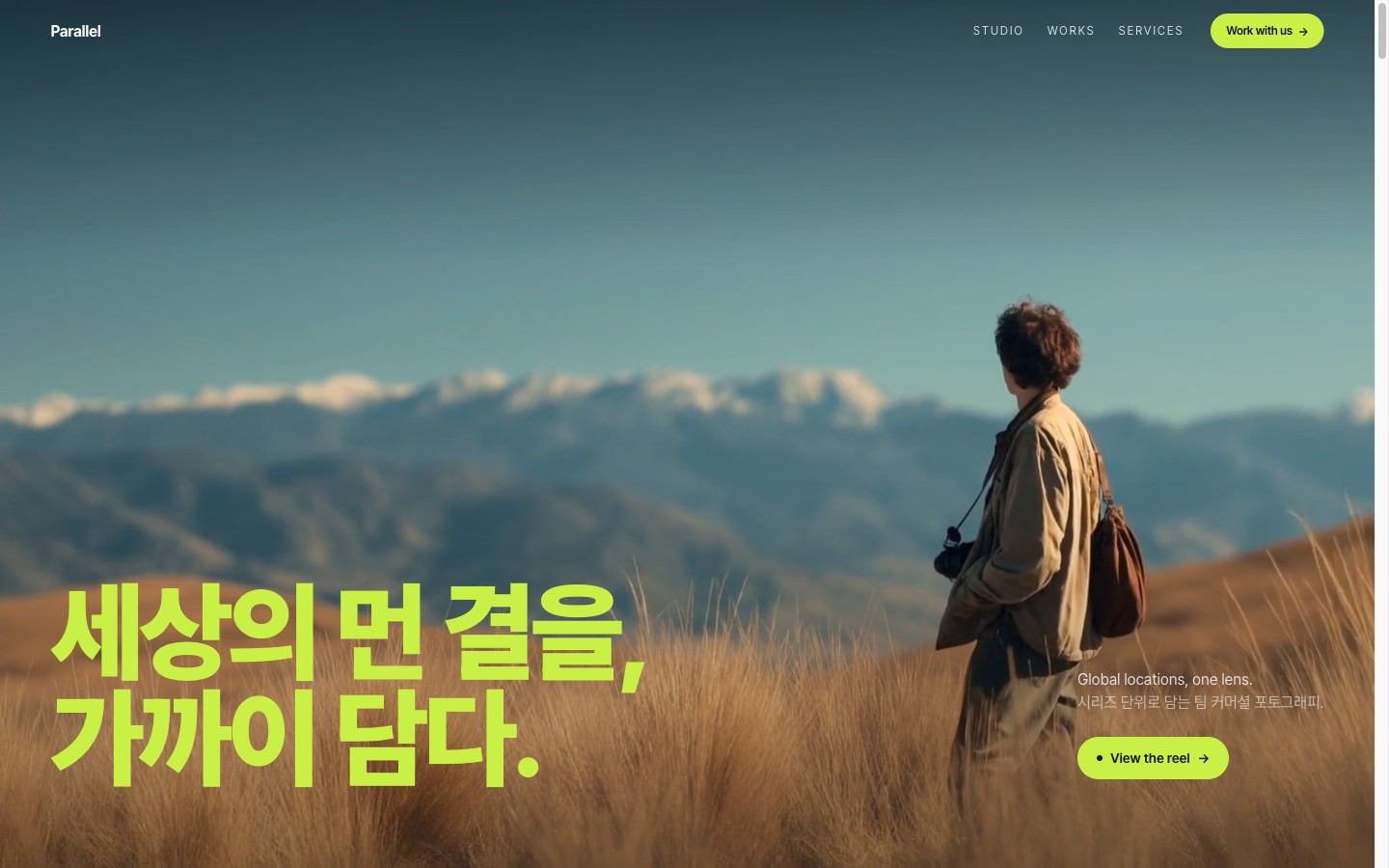Parallel 히어로 — 산맥과 풀밭 위 카메라를 든 인물